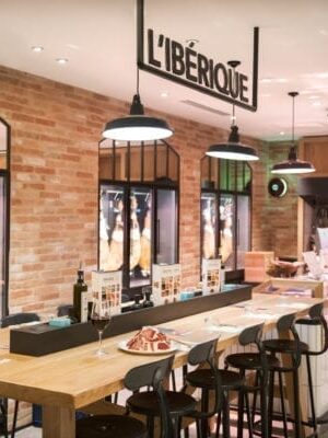 Indulge in a taste of the Iberian Peninsula, savoring ham on bar chairs at the grand grocery store.