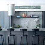 Sleek kitchen with concrete bar and stylish Chaises Nicolle industrial metal chairs