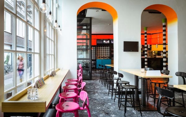 Bar d'un cinéma en Hollande avec chaise de bar rose et tabouret noir