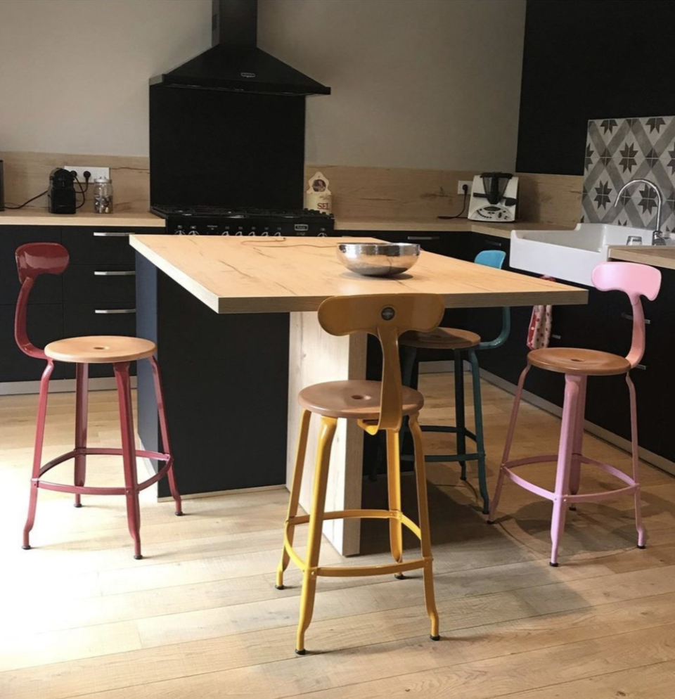 Mismatched colorful chairs made of wood and metal surrounding a kitchen island.