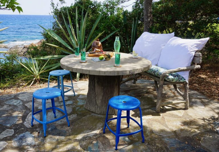 Outdoor metal chair Nicolle, 18-inch in height, next to an outdoor concrete table and another metal chair.