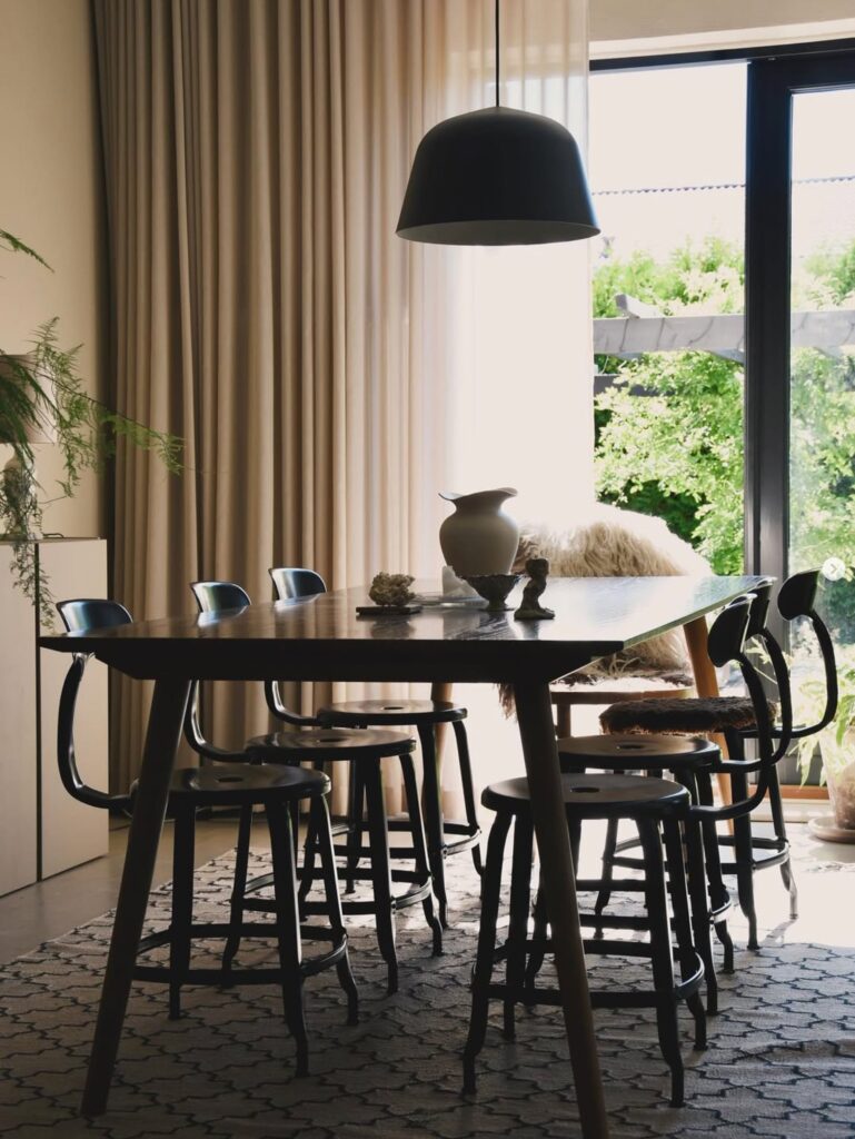 Salle à manger moderne avec chaises et lumière naturelle.